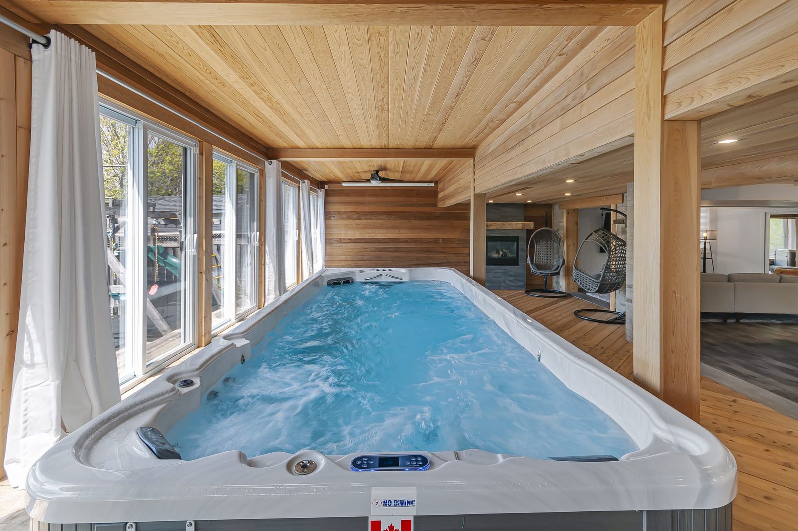 Indoor swim spa in a cedar-lined sunroom