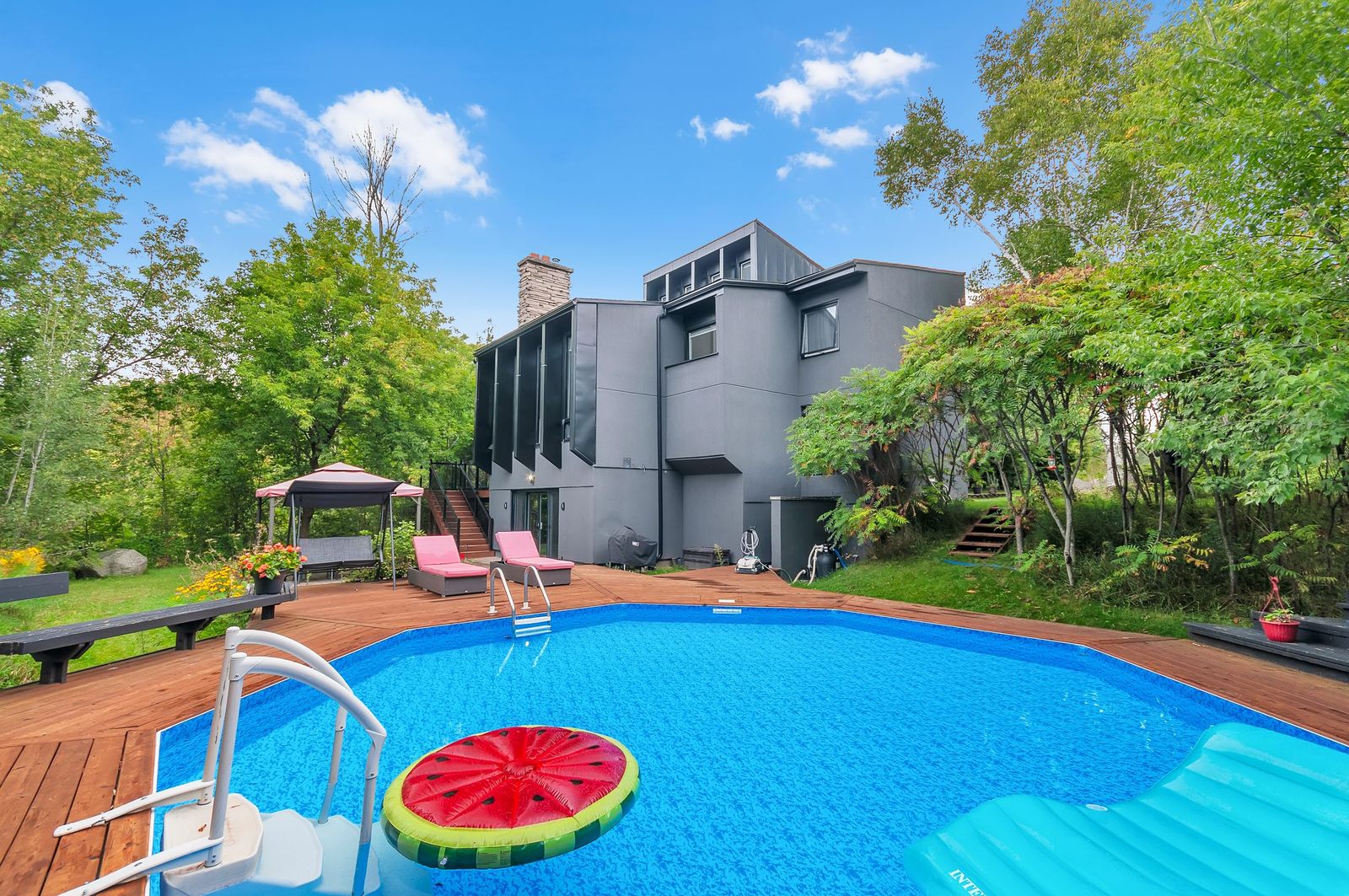 Backyard pool with deck and mature trees