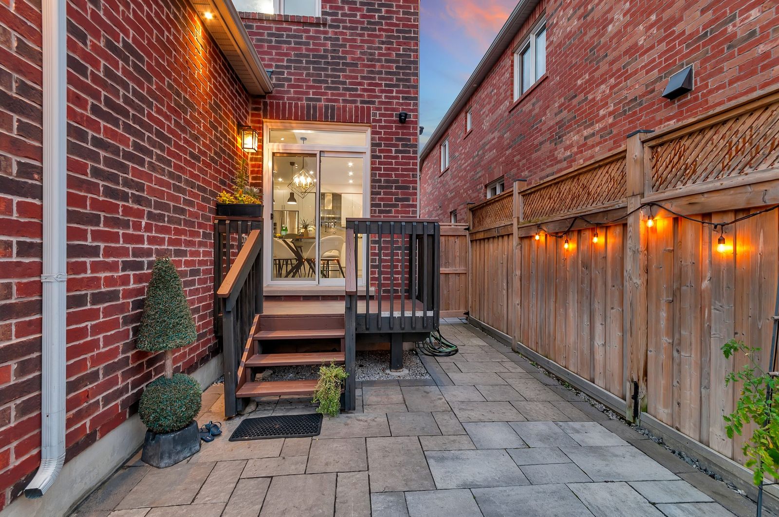 Side entrance and walkway at dusk with fence lighting