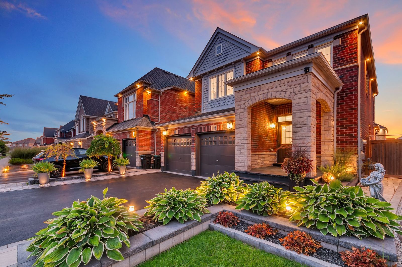Real twilight exterior with lit garden beds and warm windows