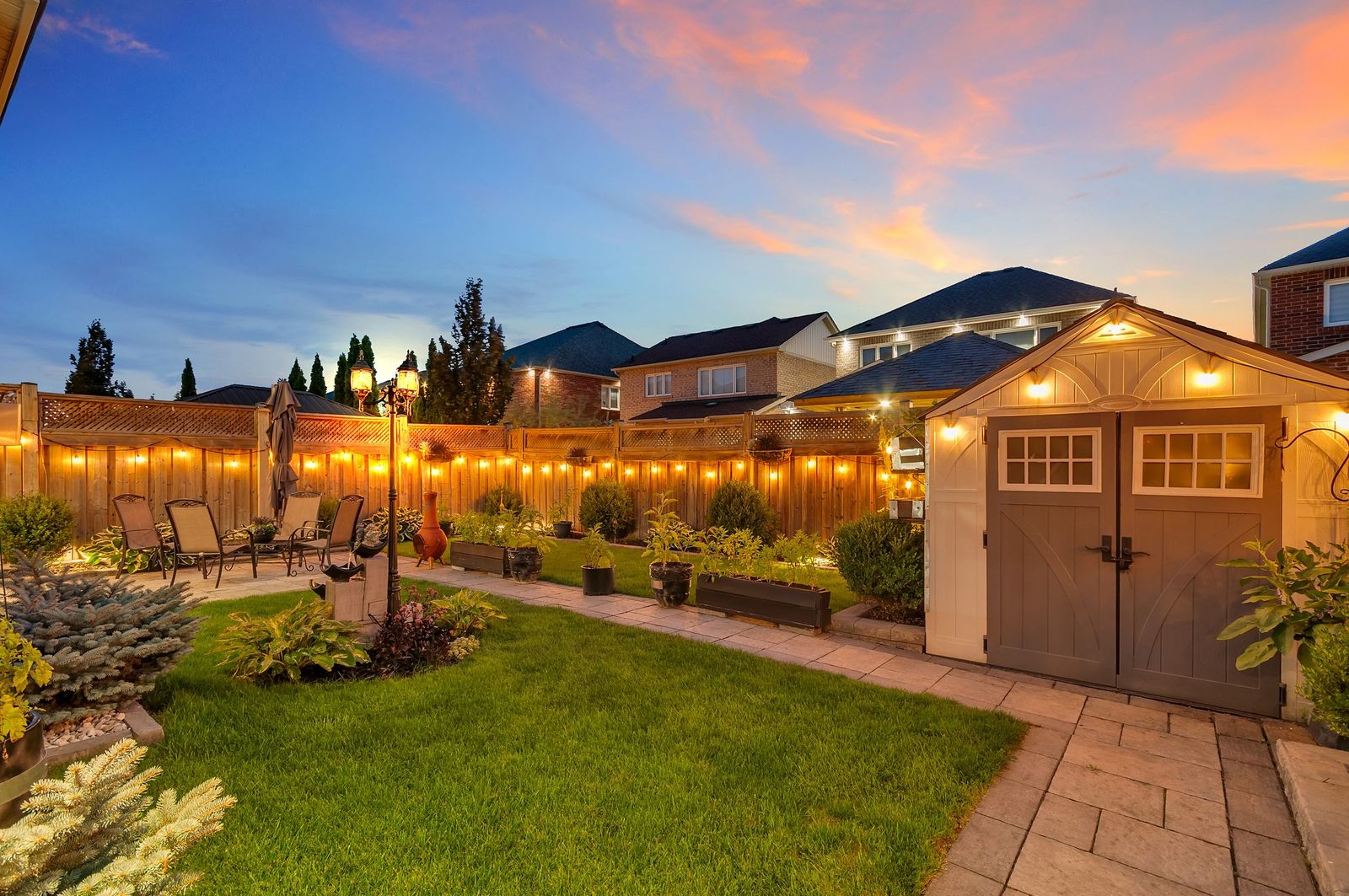 Backyard and garage at twilight with landscape lighting