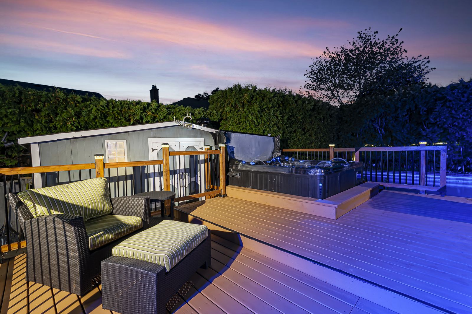 Backyard deck, hot tub and lit pool at real twilight